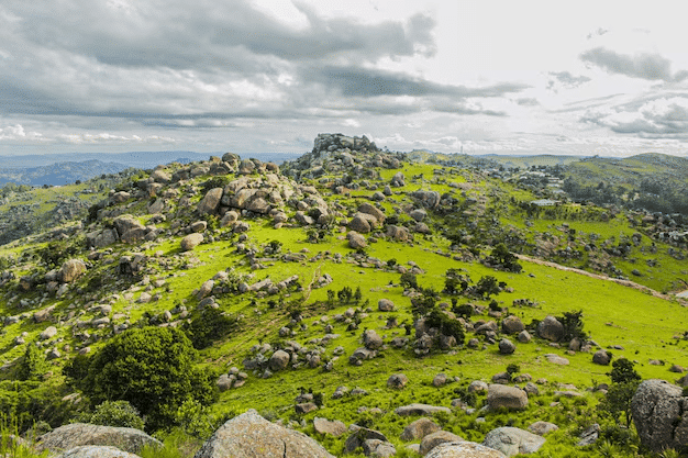 Des collines verdoyantes parsemées de rochers massifs sous un ciel nuageux dans les hauts plateaux d'Eswatini.