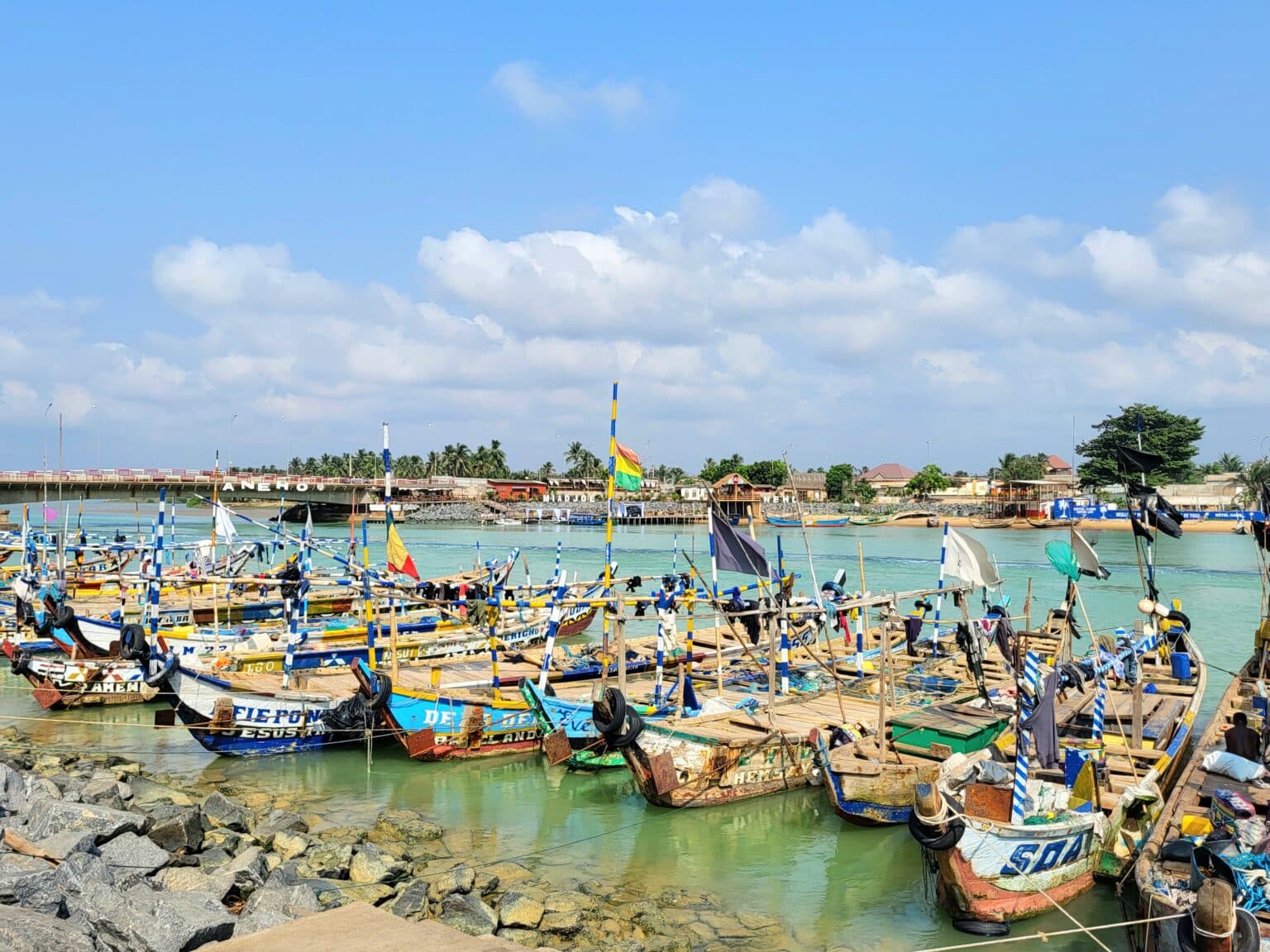 Alignement de pirogues de pêche colorées amarrées sur une eau turquoise à Aného, au Togo.