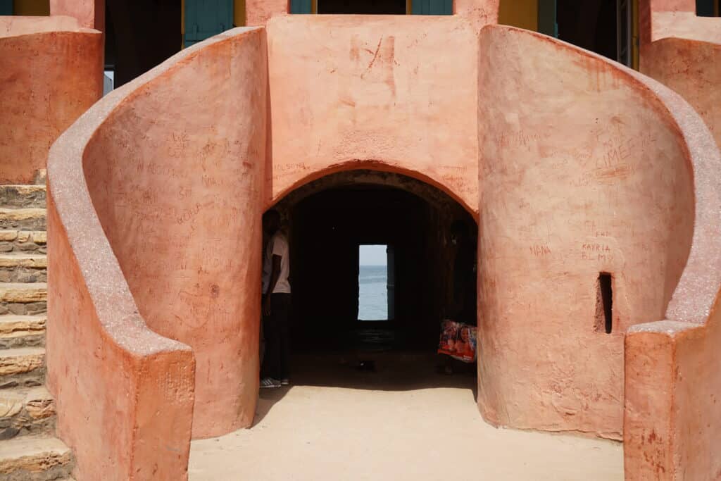 Vue du Castel de l'île de Gorée, une fortification historique en pierre dominant une plage de sable au Sénégal.