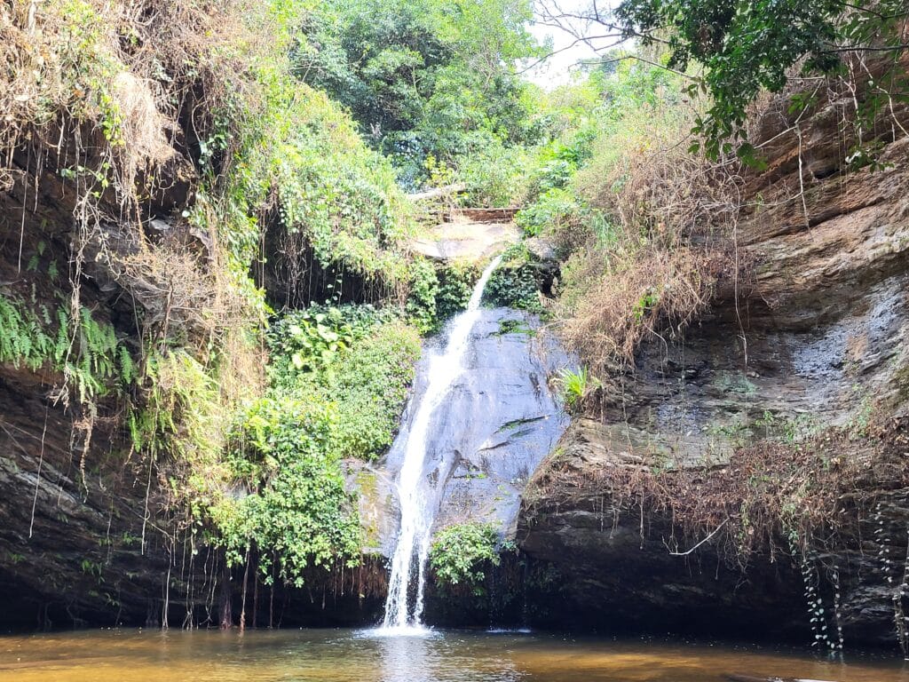 Cascade naturelle s'écoulant sur une paroi rocheuse sombre entourée d'une végétation dense à Kpimé, au Togo.