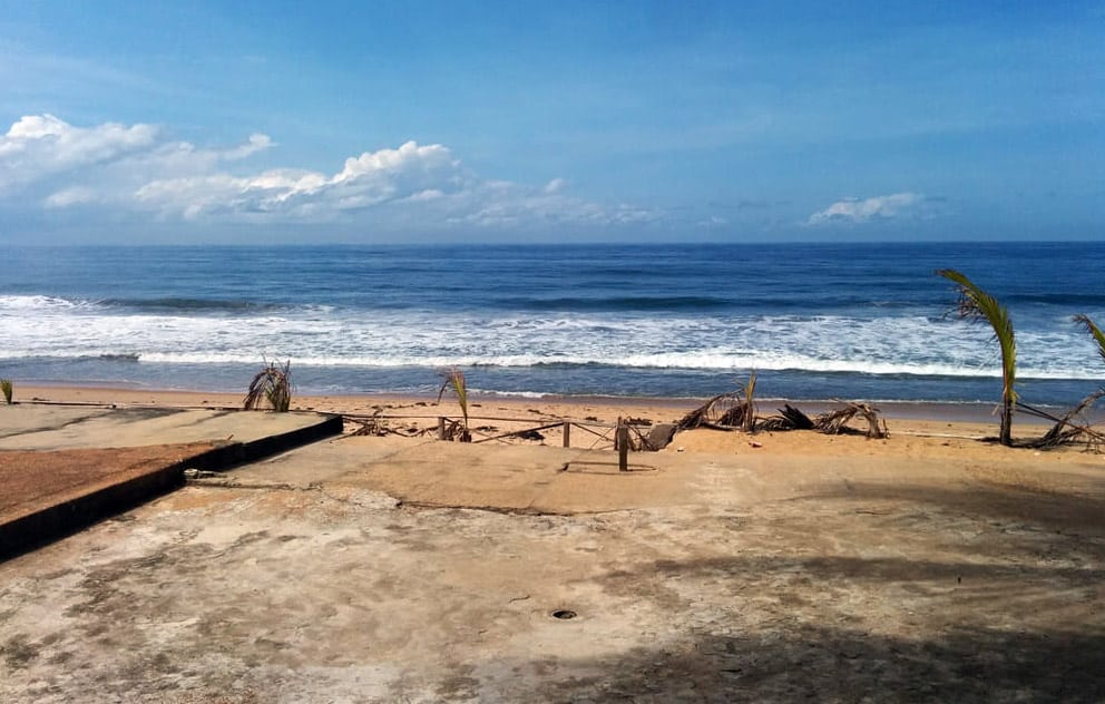 Vue sur l'océan Atlantique depuis une terrasse en béton bordée de palmiers sur la plage de Grand-Bassam.
