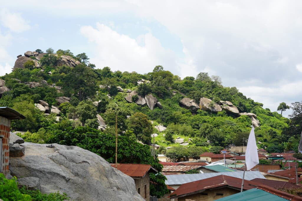 Vue sur les toits d'un village béninois niché au pied de collines granitiques massives couvertes de végétation à Dassa-Zoumè.