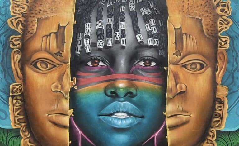Fresque murale colorée représentant un visage féminin africain stylisé entre deux masques traditionnels. Le visage central est orné de peintures faciales vives, avec des tresses décorées de perles blanches, entouré de deux grands masques aux teintes ocres évoquant l’art royal béninois.
