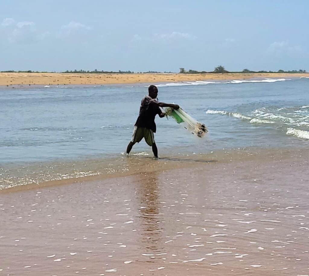 Un pêcheur béninois lançant son filet à la main dans l’embouchure du fleuve Mono à Grand-Popo, Bénin.