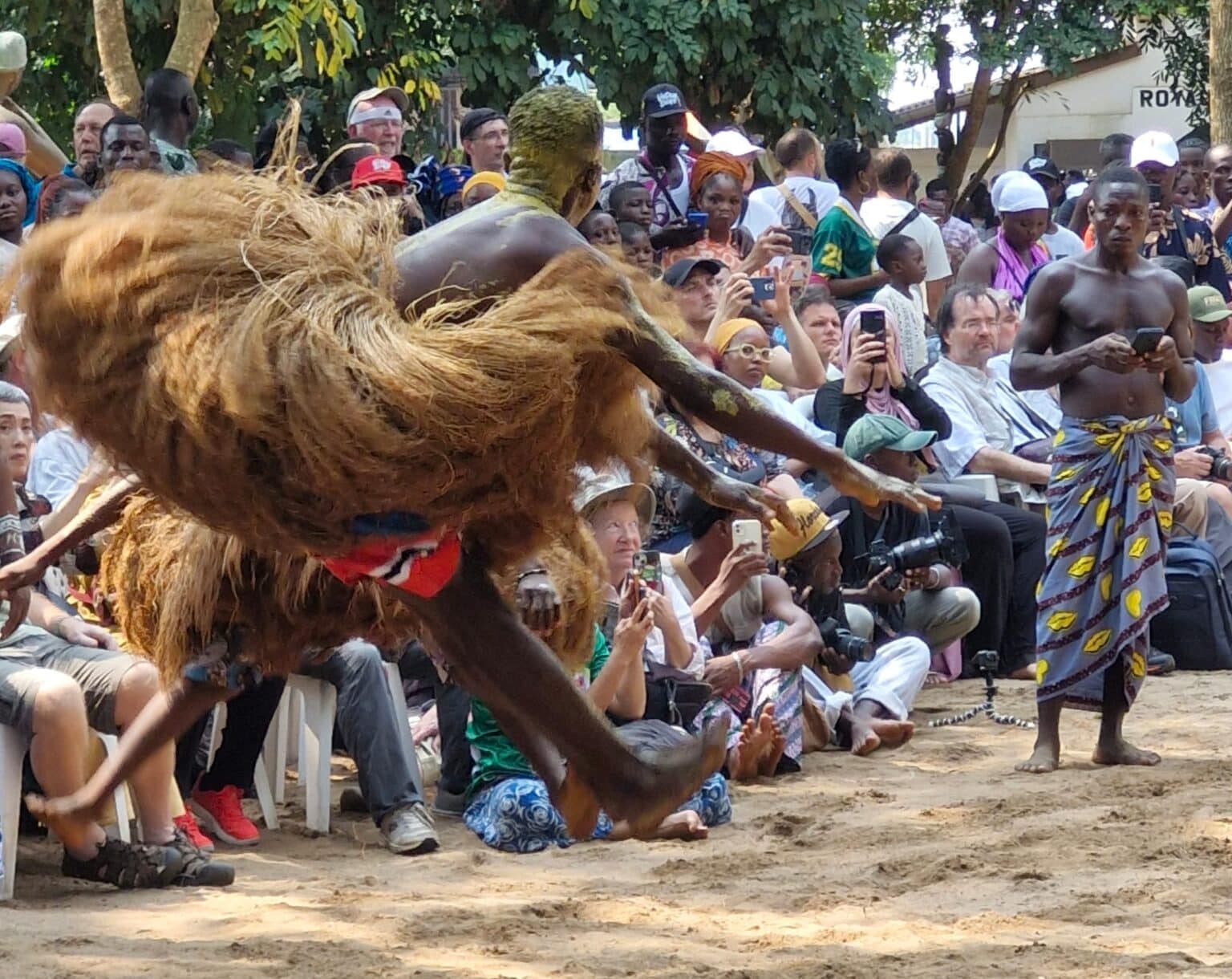 Danseur traditionnel vaudou en pleine performance lors d’une cérémonie culturelle au Bénin, entouré du public pendant les festivités vaudou days 2026