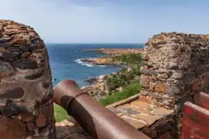 Vue depuis les remparts en pierre du Fortaleza Real de São Filipe montrant un canon ancien pointé vers la côte escarpée et l'océan Atlantique à Cidade Velha, Cap-Vert.