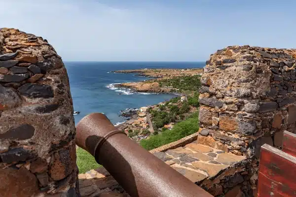 Vue depuis les remparts en pierre du Fortaleza Real de São Filipe montrant un canon ancien pointé vers la côte escarpée et l'océan Atlantique à Cidade Velha, Cap-Vert.