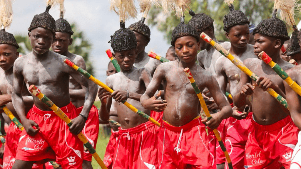 Jeunes initiés togolais, en shorts rouges, dansant avec des bâtons lors de la cérémonie de l'Évala en pays Kabyè.