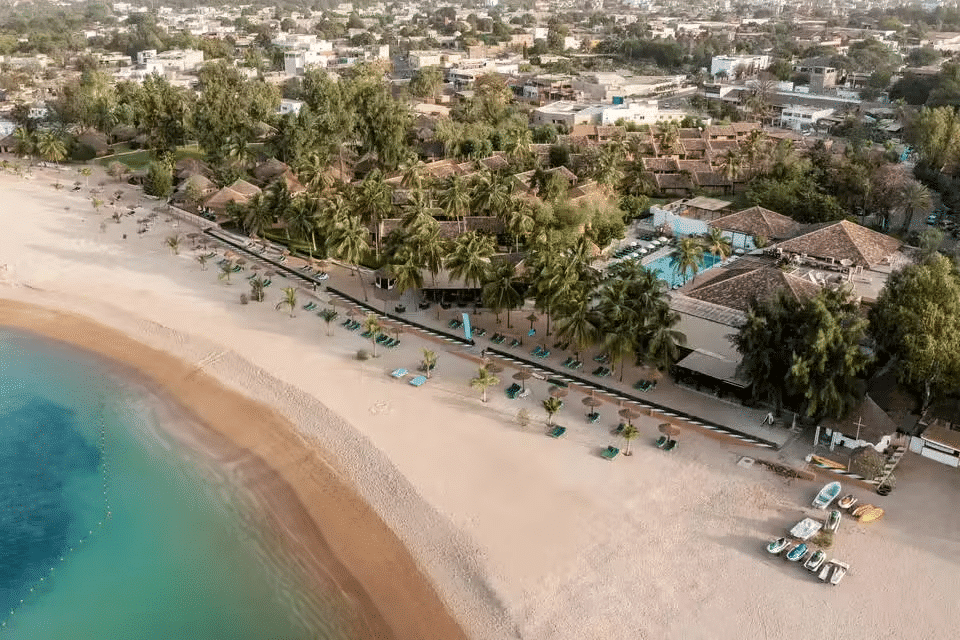 Vue aérienne d'une plage de sable fin bordée de cocotiers et d'un complexe hôtelier au Cap Skirring, Sénégal.