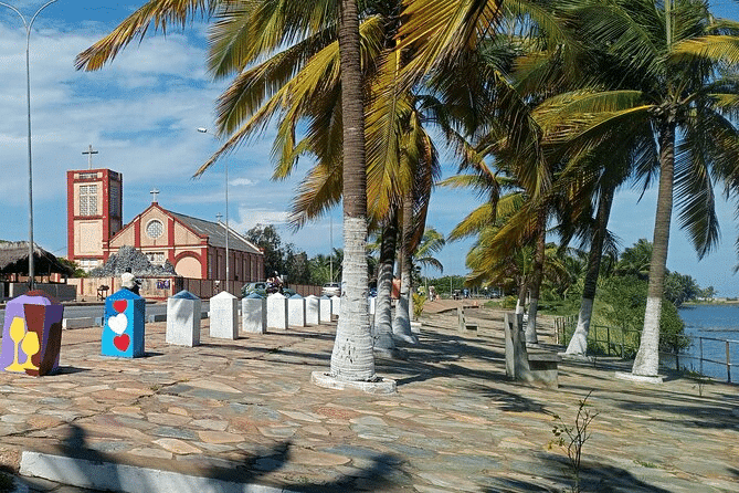 Vue de la promenade en pavés bordée de palmiers à Agbodrafo, avec l'église historique de Togoville en arrière-plan au Togo.