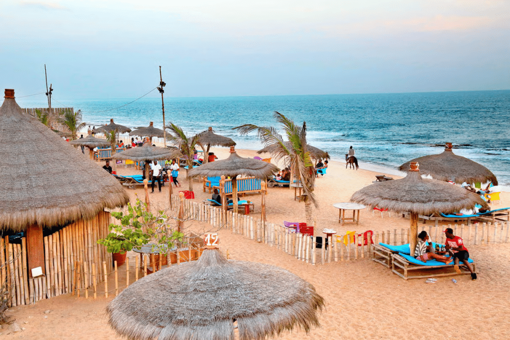 Vue aérienne d'une plage de sable fin bordée de paillotes en chaume et de palmiers face à l'océan au Togo.