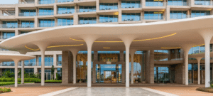 Entrée luxueuse avec un auvent blanc moderne et colonnes blanches devant la façade vitrée d'un hôtel à Cotonou.