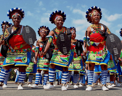 Femmes Zouloues en costumes colorés tenant des boucliers lors d'une danse.