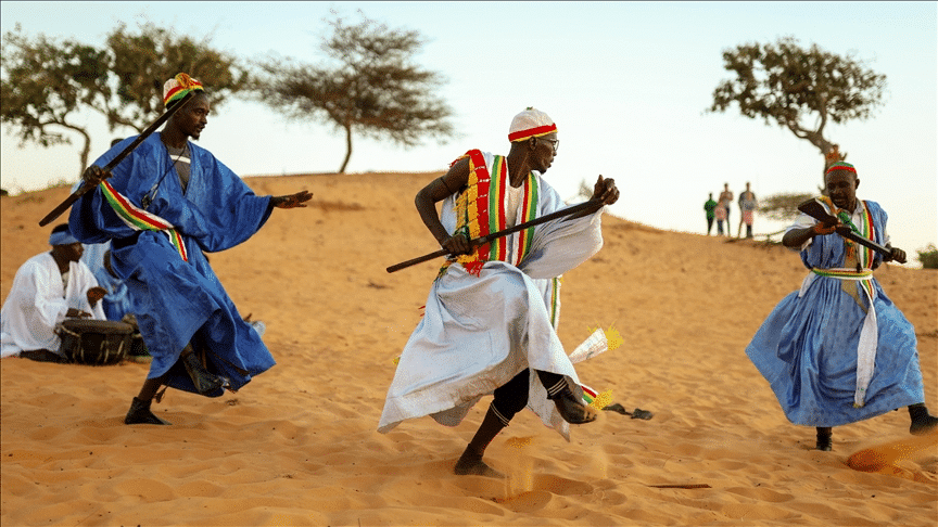 Hommes mauritaniens en boubous bleus exécutant une danse de l'épée.
