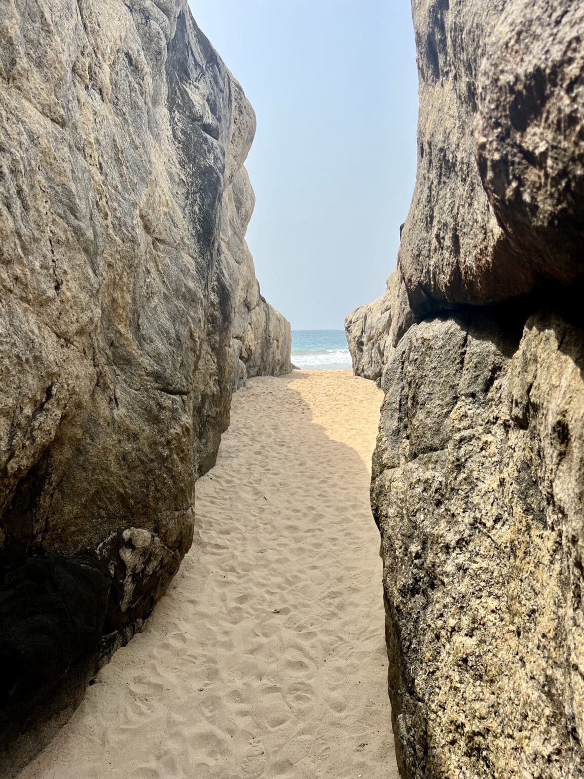 Passage naturel entre deux immenses rochers menant à une plage de sable fin et à l’océan à San-Pédro, en Côte d’Ivoire.