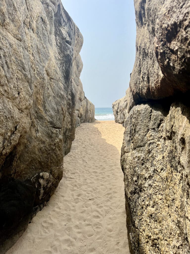 Passage naturel entre deux immenses rochers menant à une plage de sable fin et à l’océan à San-Pédro, en Côte d’Ivoire.