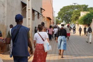 Groupe de voyageurs marchant dans une rue pavée de Ouidah pendant le festival des Vodoun Days au Bénin.