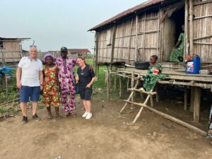 Rencontre entre voyageurs et une famille béninoise devant une maison sur pilotis en bambou au Bénin.
