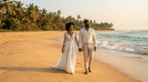 Un jeune couple afro-descendant, fraîchement marié, marche main dans la main sur le sable doré d'une plage sauvage de Grand-Popo au Bénin, au coucher du soleil. L'épouse porte une robe blanche de mariée légère et élégante, et l'époux vêt une tenue de lin claire. L'océan Atlantique et des cocotiers tropicaux forment un arrière-plan romantique et intimiste.